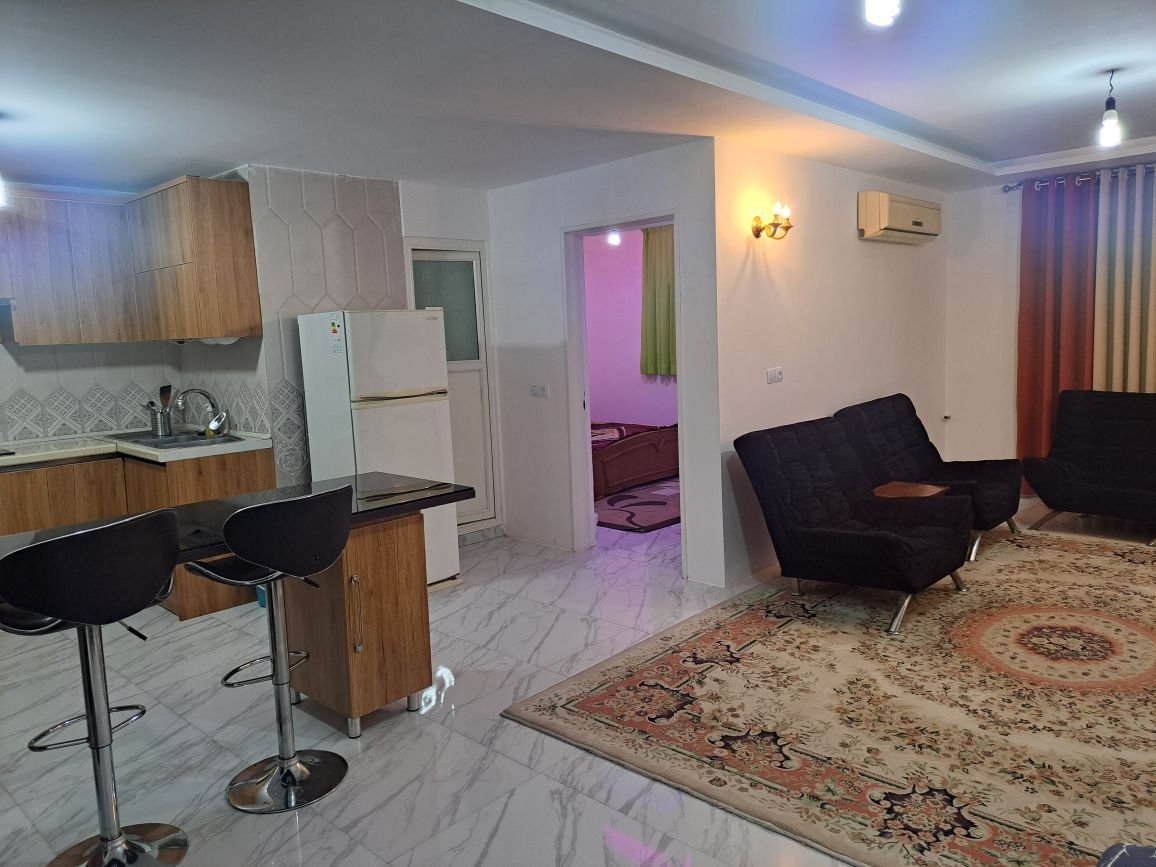 ویلا یک خوابه سرای شمشاد - نمایی از پذیرایی مبلمان درب اتاق خواب درب سرویس بهداشتی و حمام ، یخچال ، آشپزخانه و میز اُپن